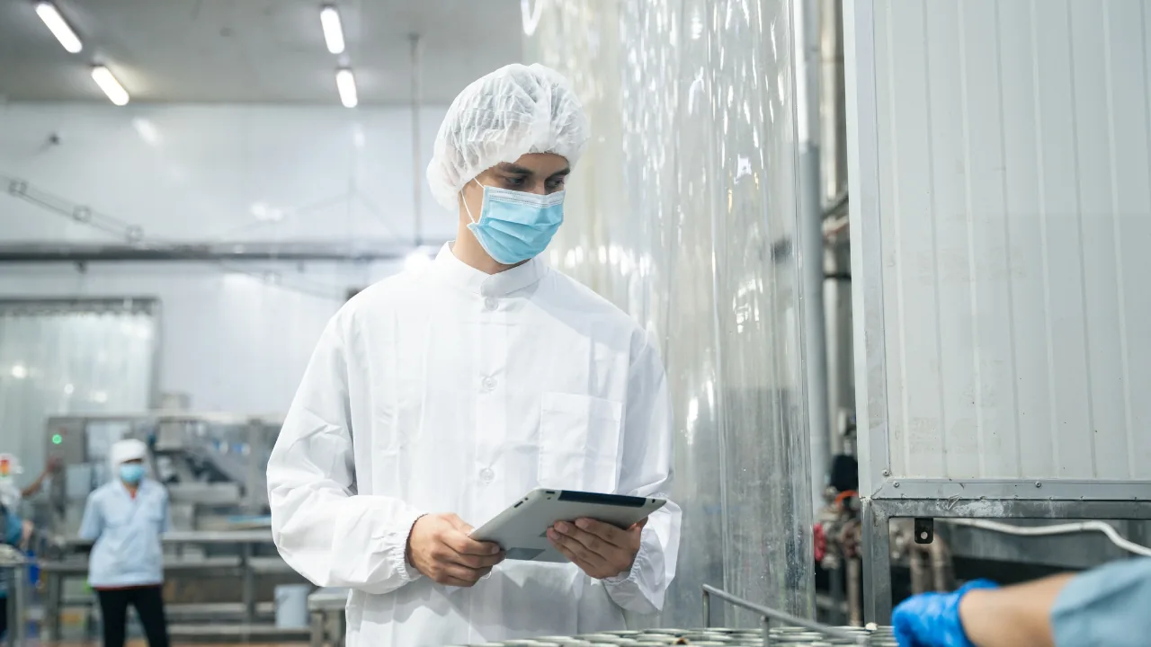 Operator in a pharmaceutical cleanroom consulting a tablet